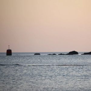 silhouette of rock formation on sea during sunset